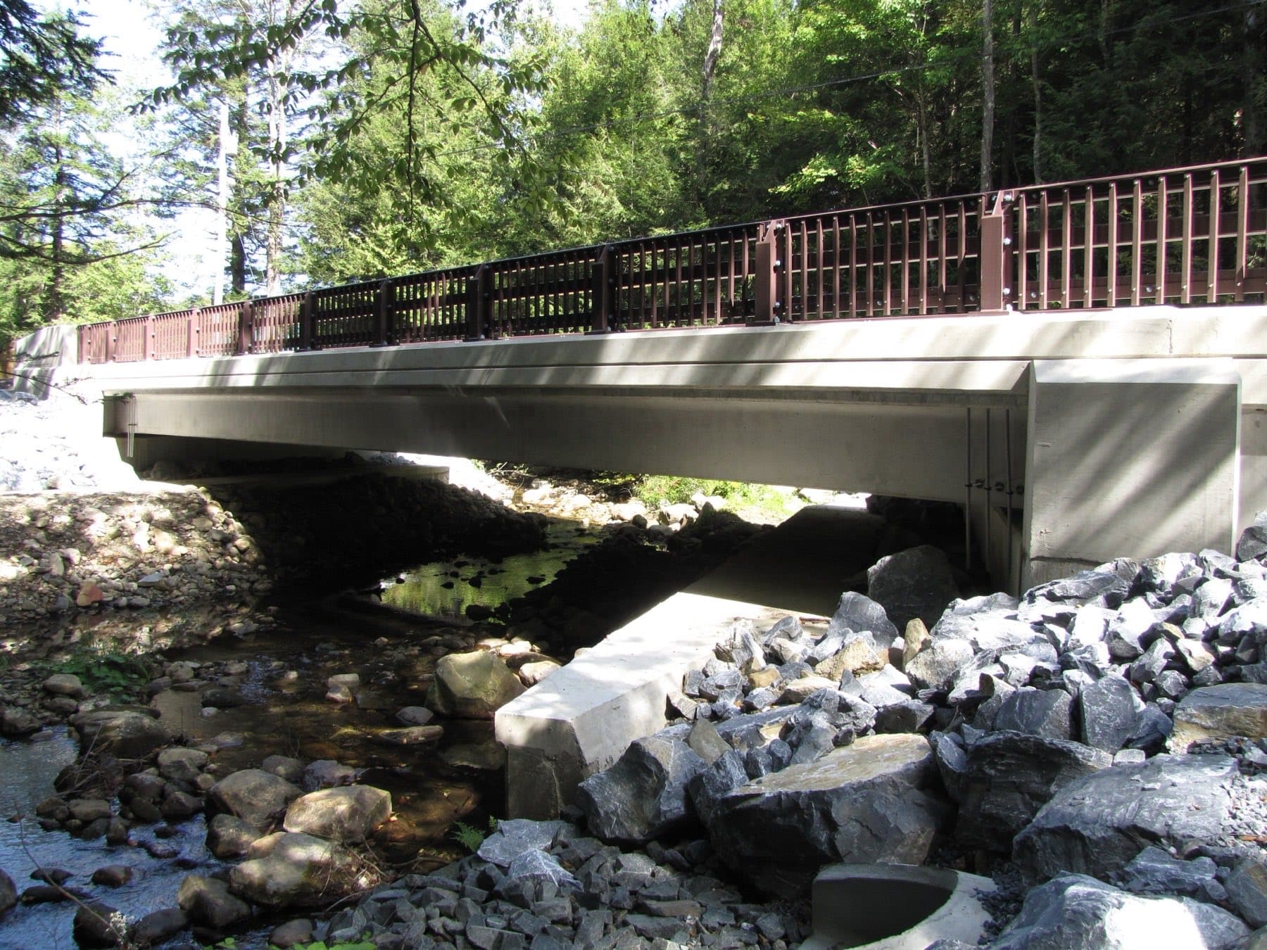 A completed 100% precast concrete bridge over a creek